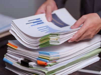 A man sits at his desk at home at night, working on his laptop. He views charts, checks documents